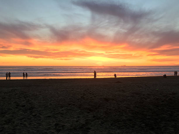 San Francisco, USA - April 16, 2016: Sunset on San Francisco's Ocean Beach. Photo contains several people walking along the beach.