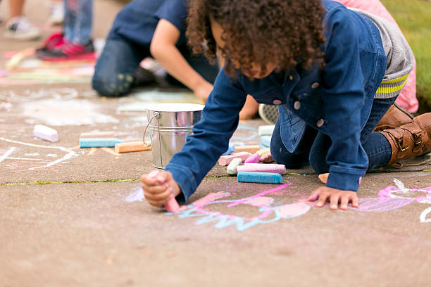 istock Young girl drawing chalk on a sidewalk 587224946