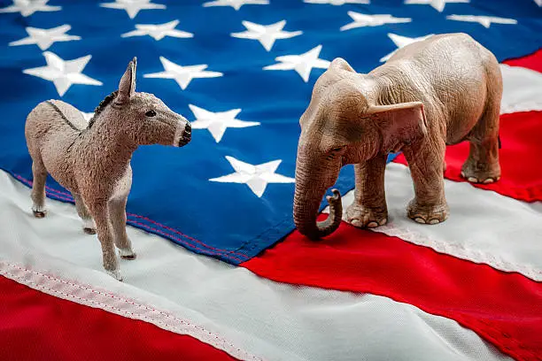 Democrats vs republicans are facing off in a ideological duel on the american flag. In American politics US parties are represented by either the democrat donkey or republican elephant