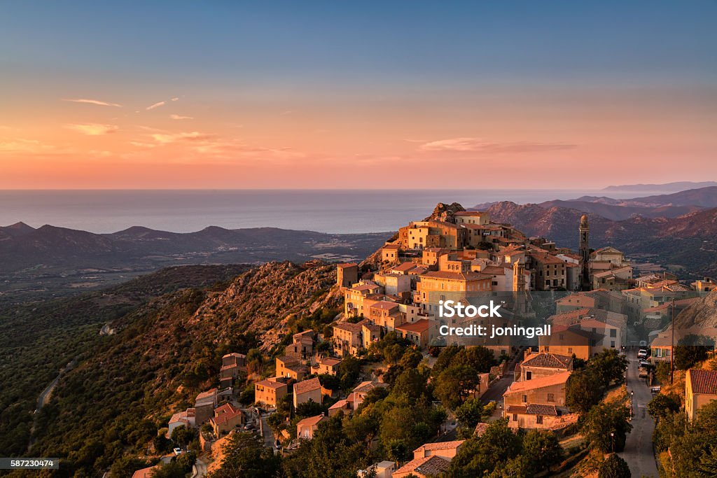 Evening sunshine on mountain village of Speloncato in Corsica The Balagne village of Speloncato in Corsica bathed in late evening sunshine with the Regino valley and Mediterranean sea behind and pink, orange and deep blue skies above Corsica Stock Photo