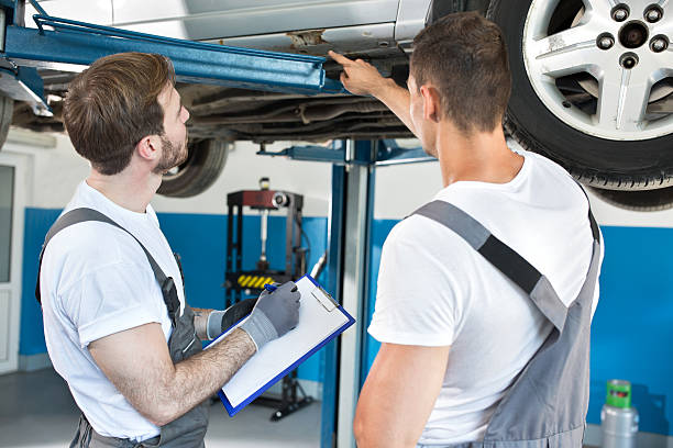 istock Auto workshop mechanics inspecting damage to car 587230896