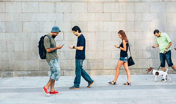 Playing a game on the phone A small group of people playing a game on their smart phones and walking around the city. battery charger photos stock pictures, royalty-free photos & images