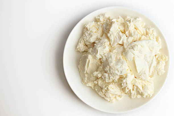 istock Cottage cheese in white saucer on white background. 587231334