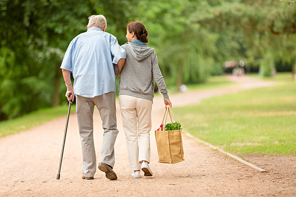 caregiver – woman helping senior man with shopping - zorg stockfoto's en -beelden