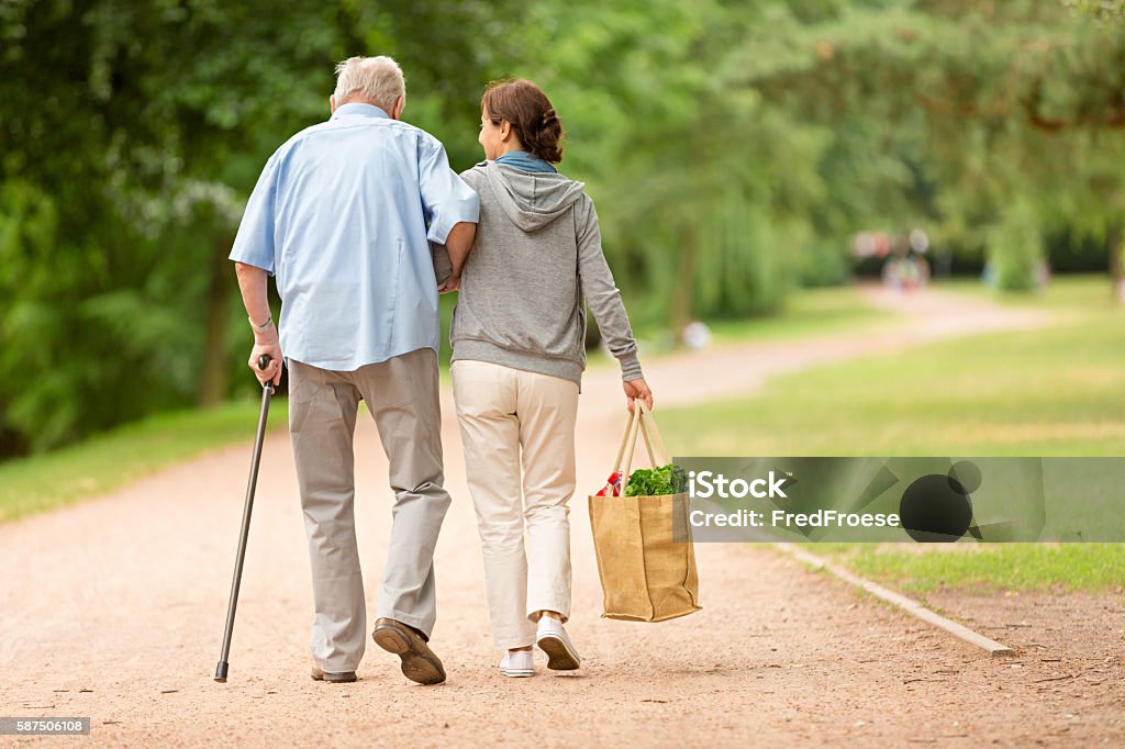 Caregiver – woman helping senior man with shopping Senior Adult Stock Photo
