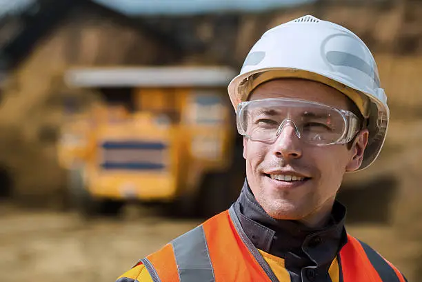 Mine worker with huge truck on the background in open pit