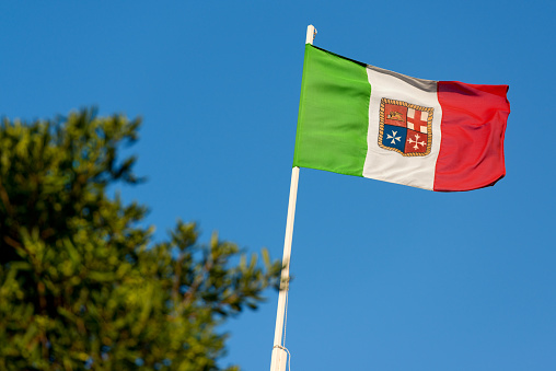 Italian flag with emblem of the four Maritime Republics, Venice, Genoa, Pisa and Amalfi, on a blue sky