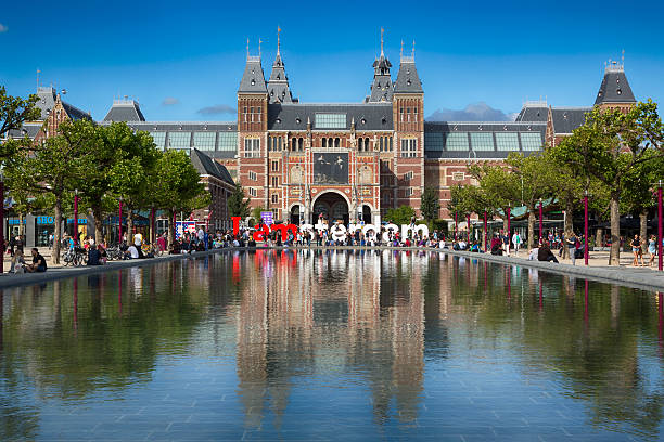Amsterdam, Netherlands - July 2, 2012: Rijksmuseum. It is a Dutch national museum dedicated to arts and history. The museum is located at the Museum Square (Museumplein) in the borough Amsterdam South. People are enjoying a beautiful day outside.