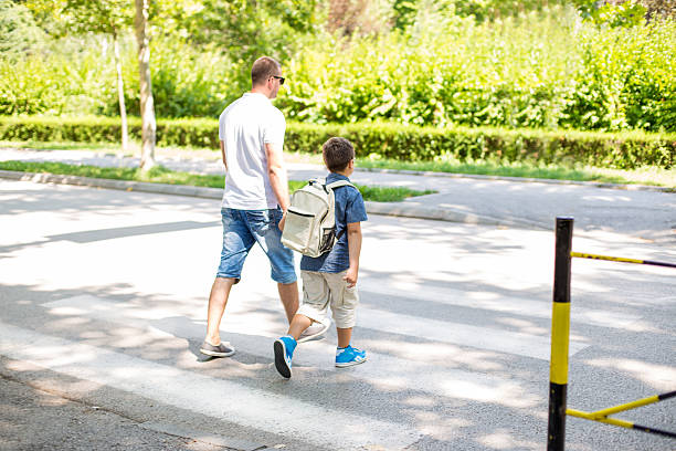 istock Boy crossing the street with his father 587516104