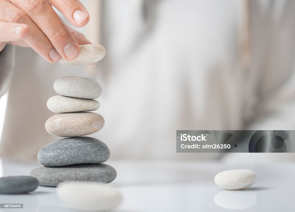 Personal Development Concept Horizontal image of a man stacking pebbles on a table with copyspace for text. Concept of personal development or self realization. Stacking Stock Photo