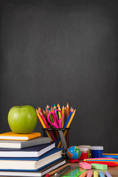 School Supplies with Apple and Chalkboard Stack of books and school supplies in front of a black chalkboard eraser photos stock pictures, royalty-free photos & images