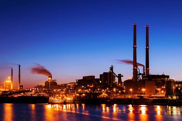 beleuchtete industrielle anlage am fluss bei nacht, amsterdam, niederlande - stahlwerk stock-fotos und bilder