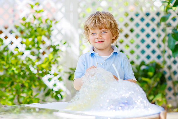 istock Happy little boy making experiment with colorful water and soap 587518632