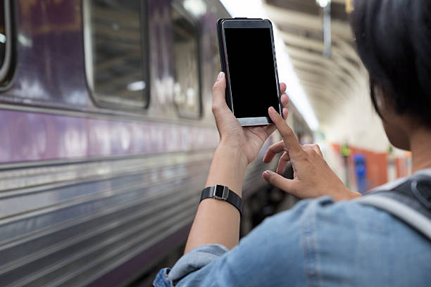 istock woman holding smartphone with backpack at train station 587518796