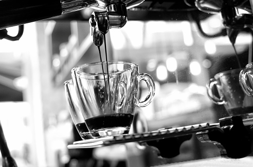 Close-up of espresso pouring from coffee machine. Professional coffee brewing.