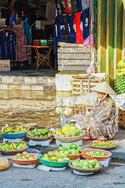 asian trader selling fresh bananas mangoes and lime - lime market vietnam fruit imagens e fotografias de stock