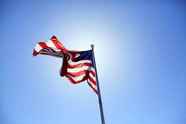 istock American flag blowing wind on the blue sky 587523918