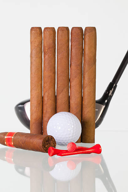 istock Golf driver and different cigars on a glass desk 587524986