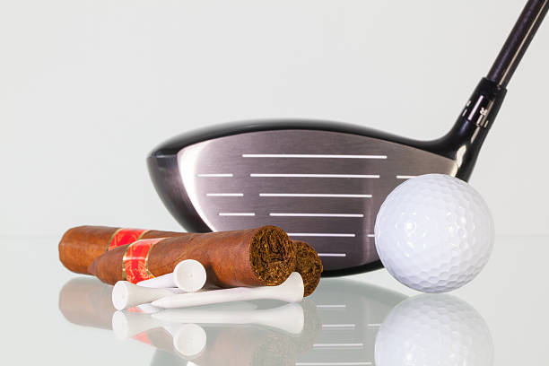 istock Golf driver and different cigars on a glass desk 587525022