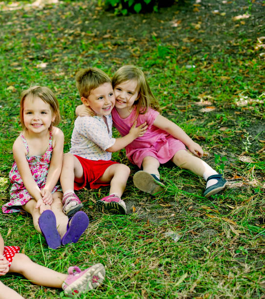 Three poor cheerful children's sitting outdoor in the nature during winter season.