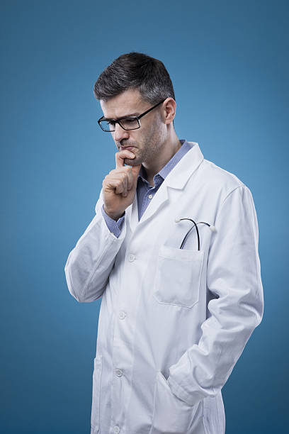 istock Pensive doctor with hand on chin 587525890