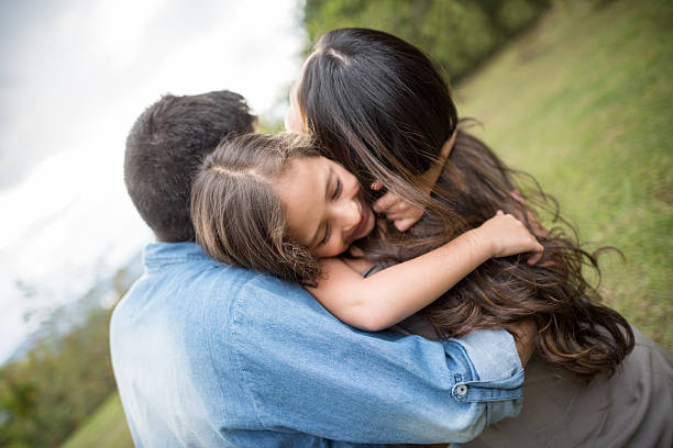 Beautiful affectionate family hugging at the park and looking very happy - relationship concepts
