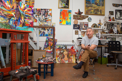 Expressionist artist in the interior of his own art studio among the paintings he created