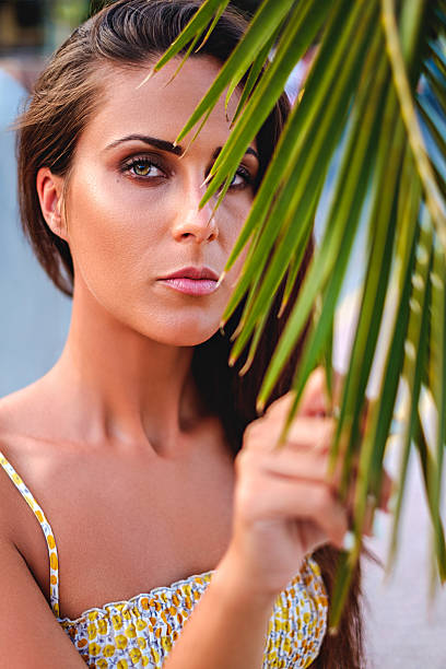 istock Girl with green eyes holding palm leaf 587527778