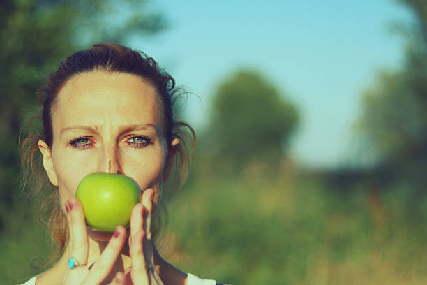 istock Young woman in nature with green apple 587530962