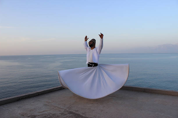 Only birds can fly? Antalya, Turkey - April 16, 2016: Whirling dervish (Ishak Urun) with the beautiful sea scenery of Antalya mevlana stock pictures, royalty-free photos & images