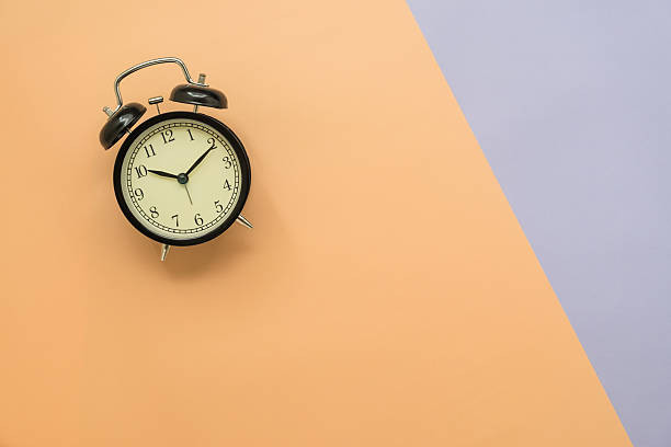istock Top view antique vintage alarm clock on orange violet background 587531992