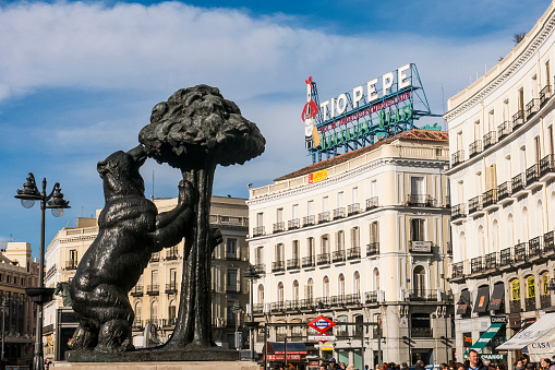 Madrid, Spain - January 24, 2015: View of the statue featuring The Bear and the Strawberry Tree with the iconic 'Tio Pepe' sign seen in the background located in Puerto del Sol, the capital city of Spain.