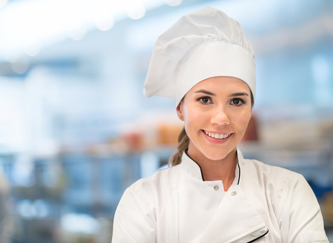 Beautiful female Chef working in a commercial kitchen and looking at the camera smiling