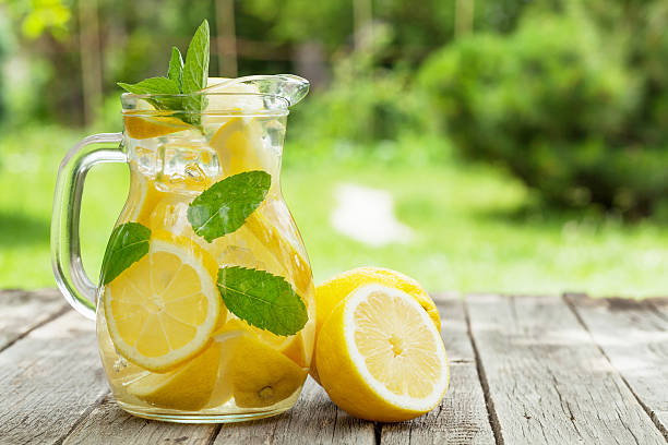 Lemonade with lemon, mint and ice Lemonade pitcher with lemon, mint and ice on garden table. View with copy space lemon soda photos stock pictures, royalty-free photos & images