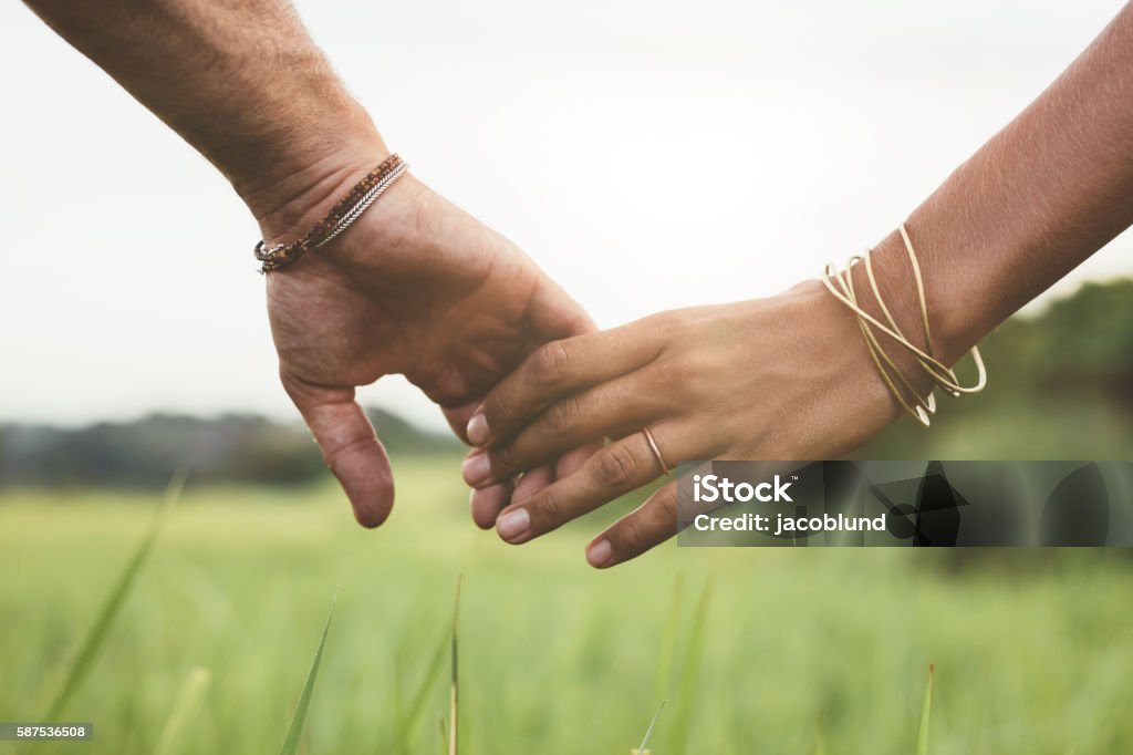 Pareja amorosa cogía de la mano en un campo - Foto de stock de Agarrados de la mano libre de derechos