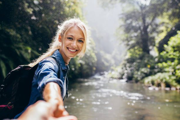 Female hiker holding hand of his boyfriend Portrait of happy young woman holding hand of her boyfriend while walking by mountain stream. Couple enjoying a hike in nature. personal perspective photos stock pictures, royalty-free photos & images
