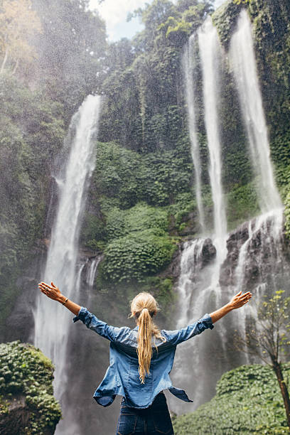 istock Excited woman standing by waterfall 587536862