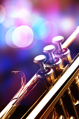 Detail of the trumpet in a jazz bar. Selective focus. Blured background. Nightbar lights in background.