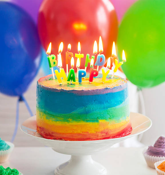 istock Rainbow cake and cupcakes decorated with birthday candles 587539834