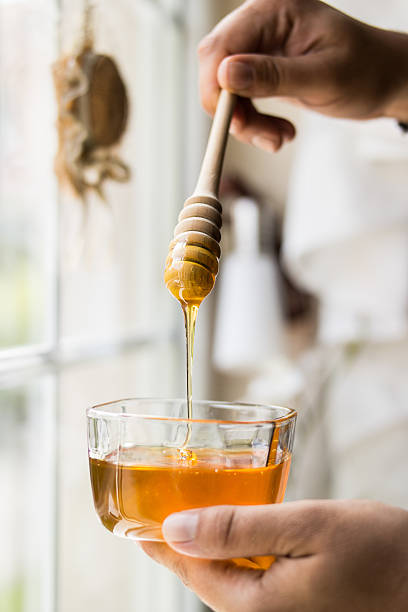 istock Honey dripping with wooden dipper 587540306