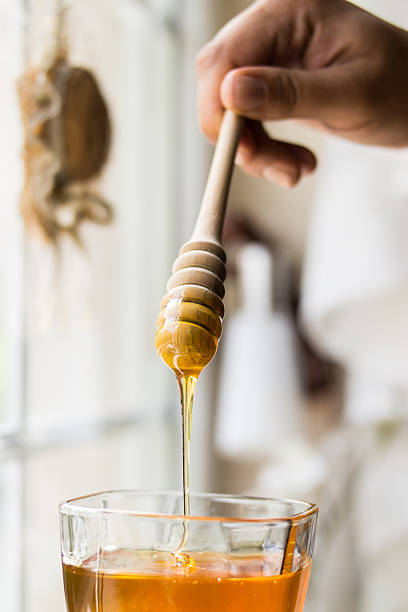 istock Honey dripping with wooden dipper 587540452