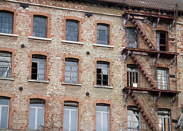 Old dilapidated industrial building made of bricks and the long rusty fire escape