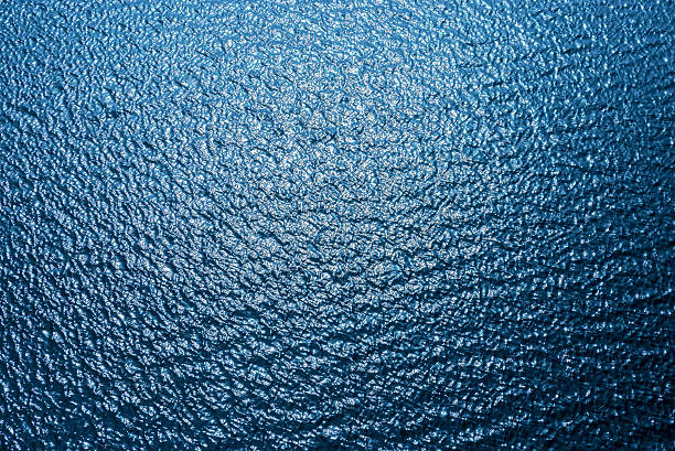 istock dark blue water with waves and sun reflections 587543880