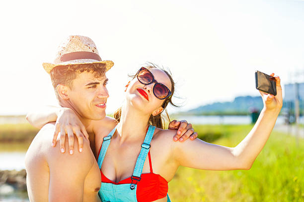 Happy young couple having fun taking selfie with smartphone outdoors.