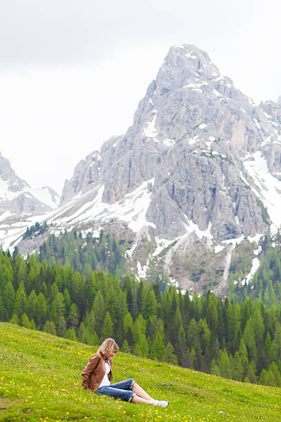 Beautiful young woman enjoy nature. Relaxing in flower garden in front of the Dolomites Alpine mountain.