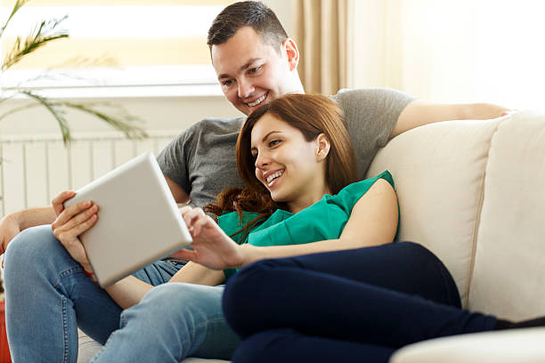 istock Happy couple using tablet on sofa in the living room 587547446