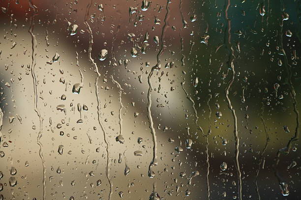 istock Rain drops on window with house and church in background 587547540