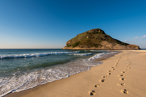 Footsteps in Sand in Recreio Beach and Pontal Rock in the Ocean, Rio de Janeiro, Brazil.