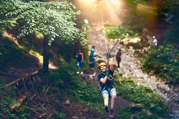 summer day with young woman on tyrolean traverse enjoying her adventure and laughing.