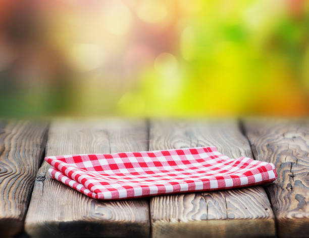 istock Red picnic cloth on wooden table mature bokeh background. 587552128